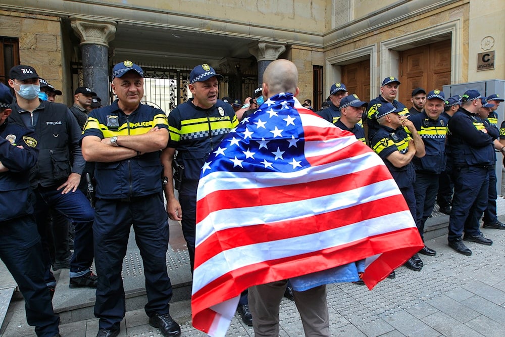 A demonstrator draped in an American flag stands in front of police during an opposition protest against the foreign influence bill at the Parliamentary building in Tbilisi, Georgia, Tuesday, May 28, 2024. (AP)