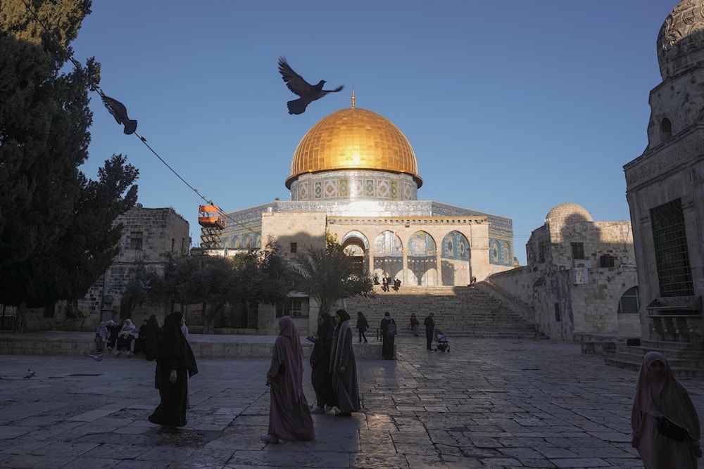 People walk next to the Dome of Rock Mosque at the al-Aqsa Mosque compound in al-Quds' Old City, occupied Palestine, March 10, 2024 (AP)