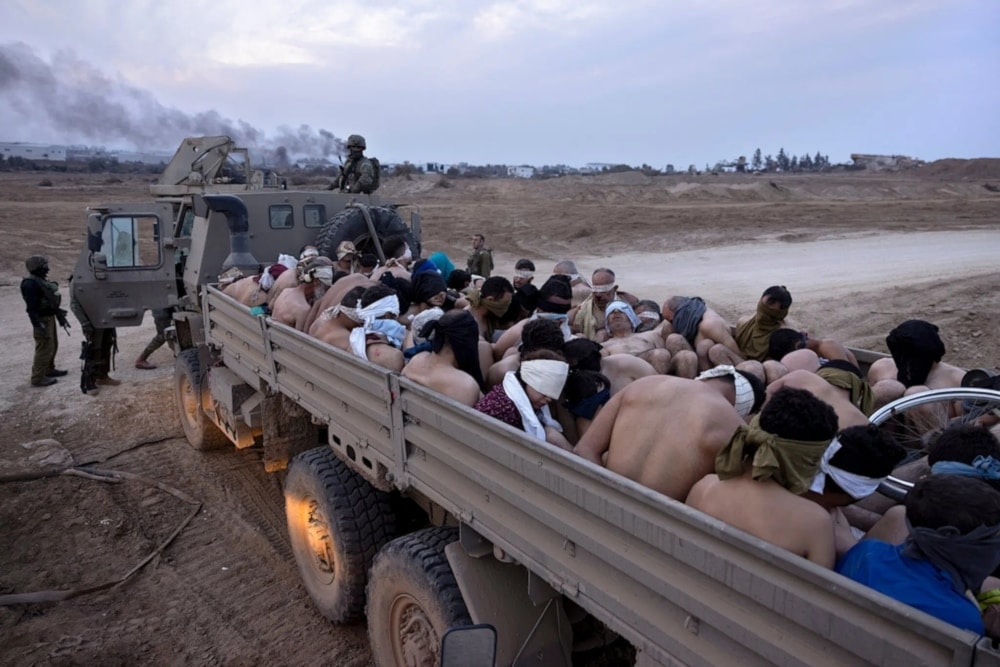 Israeli occupation forces stand next to a truck packed with bound and blindfolded Palestinian abductees in Gaza, December 2023. (AP)