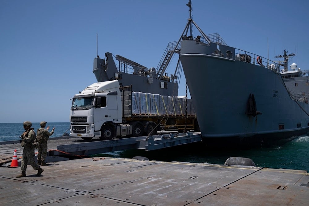 A U.S. Army soldier gestures as trucks loaded with humanitarian aid arrive at the U.S.-built floating pier Trident before reaching the beach on the coast of the Gaza Strip, Tuesday, June 25, 2024. (AP)