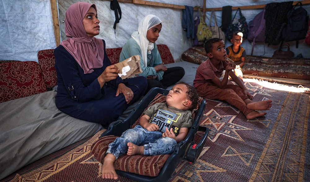 Palestinian boy Abdel Rahman Abu al-Jedian who contracted polio a month ago, sleeps surrounded by family members in their displacement tent in Deir al-Balah in the central Gaza Strip on August 27, 2024. (AFP)