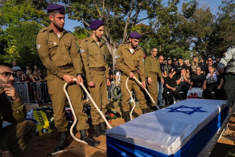 Israeli occupation soldiers lower the coffin of killed Israeli officer near Tel Aviv on November 3,2023. (AP)