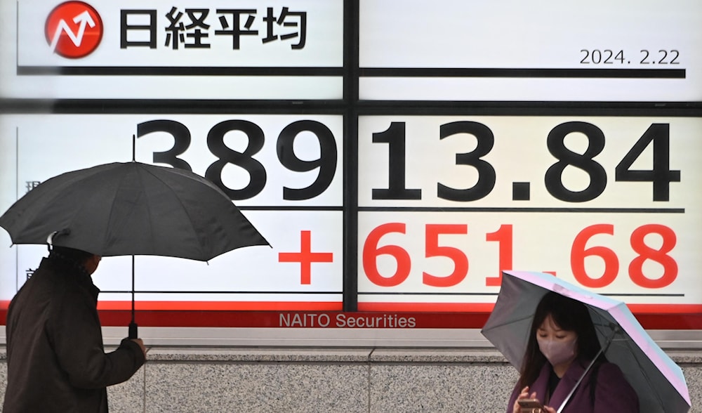 Pedestrians walk past an electronic board displaying a share price of the Tokyo Stock Exchange along a street in Tokyo on February 22, 2024. (AFP)