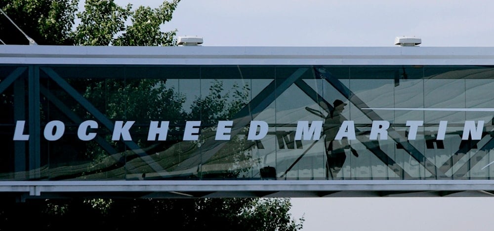 A man walks past a Lockheed Martin logo as he walks through a section of the company's chalet bridging a road at Farnborough International Airshow in Farnborough, southern England, July 19, 2006. (AP)