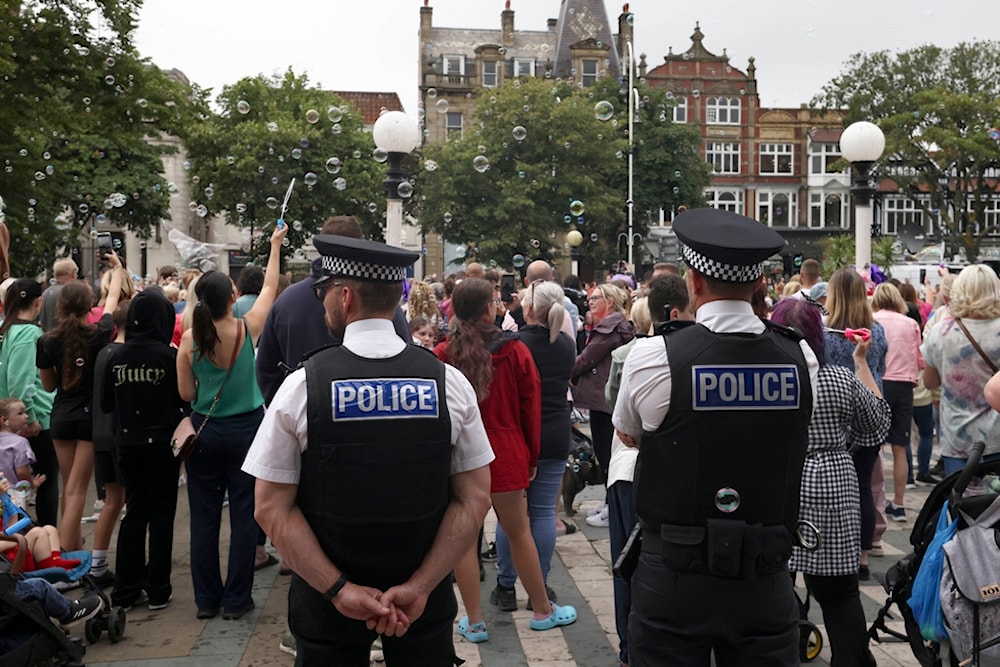 Police officers watch members of the public outside the Town Hall during a vigil to remember the victims of the stabbing attack last Monday in Southport, England, Monday, Aug. 5, 2024. (AP)