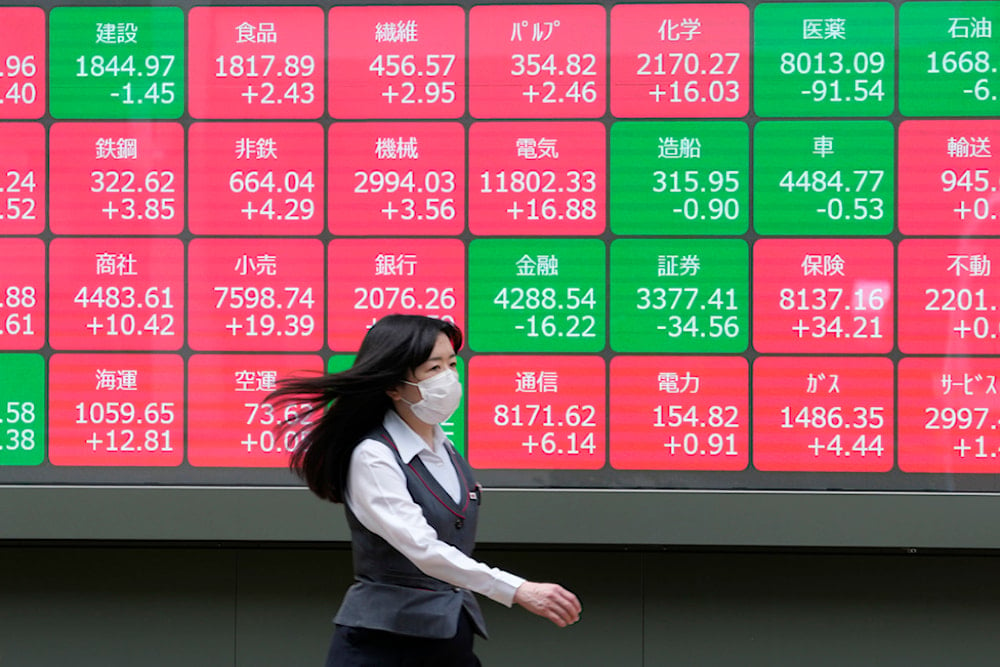 People walk past an electronic stock board showing the sectors' index of Japanese stocks outside a securities firm in Tokyo, on June 7, 2024. (AP)