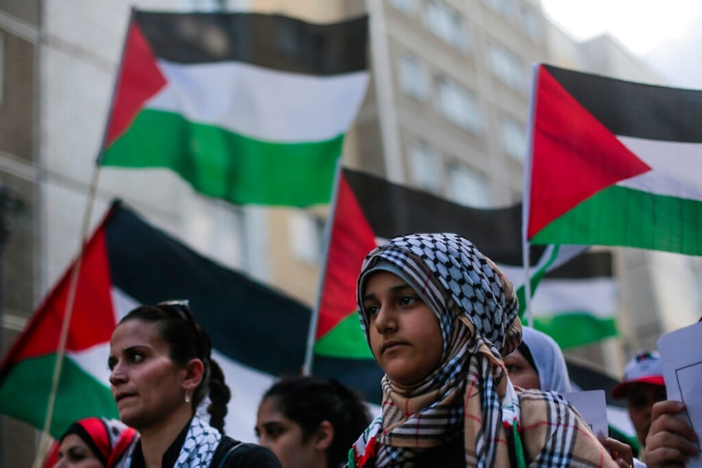 Women hold Palestinian flags during a demonstration against Israel's military offensive in Gaza, Tuesday, July 22, 2014, in Berlin, Germany (AP)