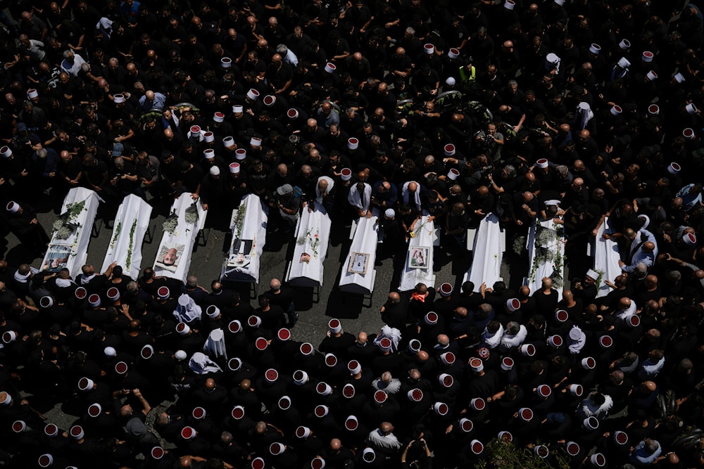 Mourners from the Druze minority surround the bodies of those killed in Majdal Shams in the Israeli-occupied Golan Heights, Sunday, July 28, 2024. (AP)