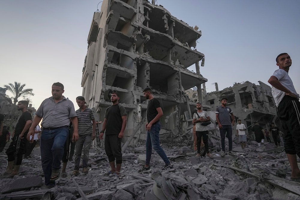 Palestinians stand in rubble after an Israeli airstrike in Deir al Balah, Gaza Strip, Tuesday, August 6, 2024 (AP)