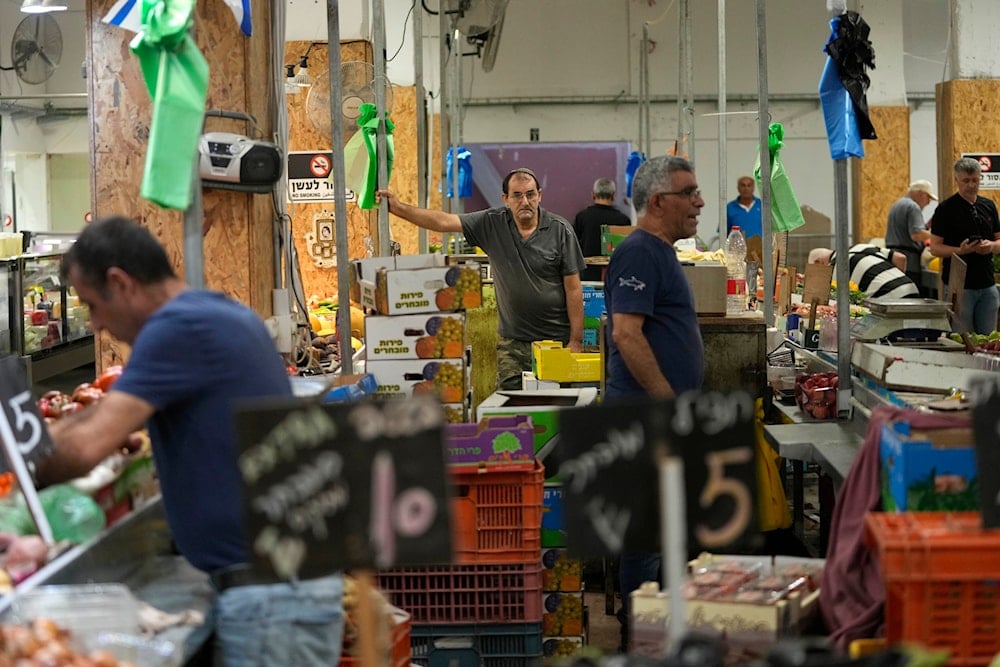 Vendors sell fruit and vegetables in a market in Haifa, occupied Palestine, Monday, August 5, 2024 (AP)