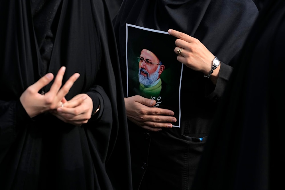 An Iranian woman holds a poster of the late President Ebrahim Raisi during a mourning ceremony for him at Vali-e-Asr square in downtown Tehran, Iran on May 20, 2024 (AP)