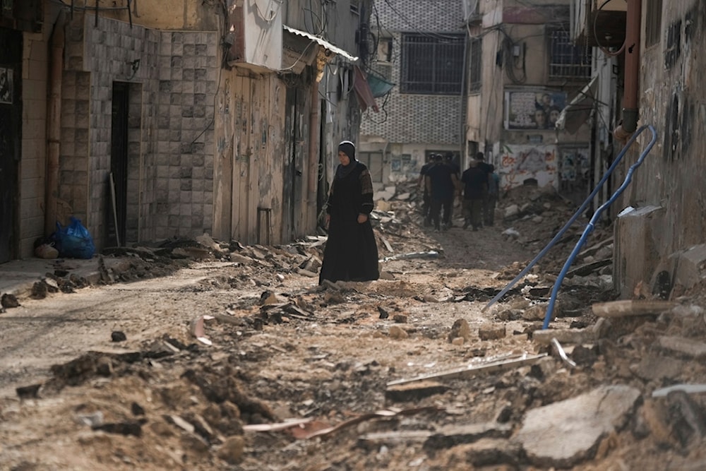 Palestinians walk on a damaged road following Israeli aggression in the West Bank city of Jenin on Friday, September 6, 2024 (AP)