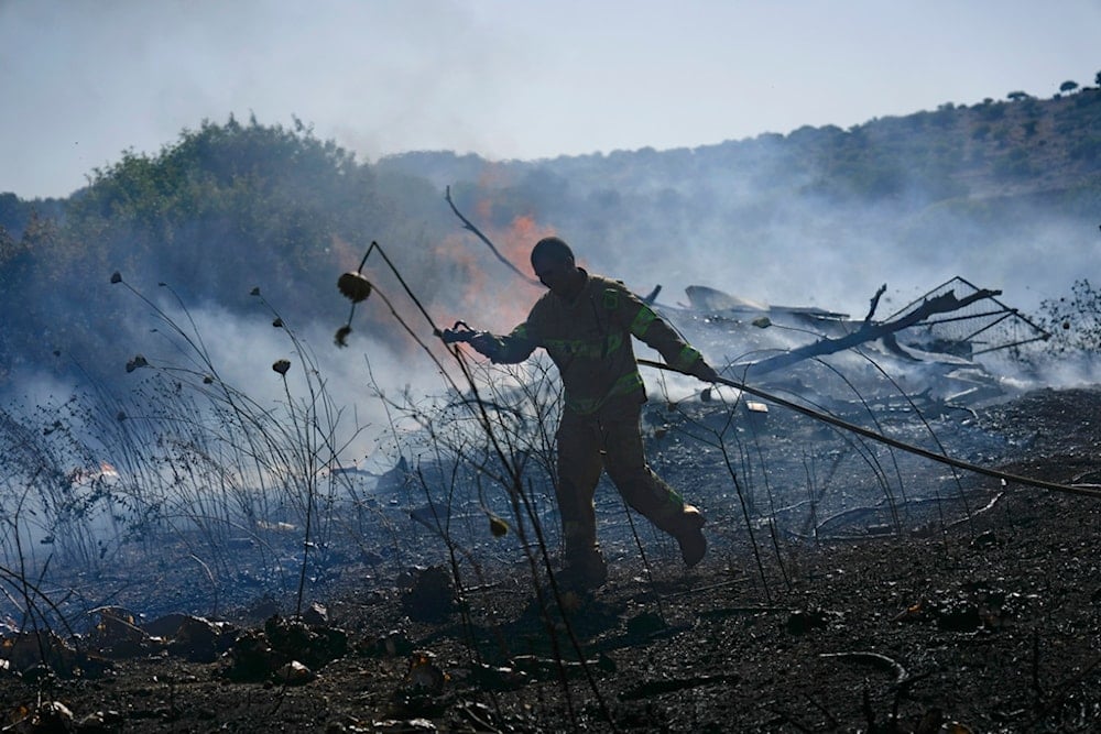 An Israeli firefighter works to extinguish a fire burning in an area near the community of Ramot Naftali, by the border with Lebanon, northern occupied Palestine, Tuesday, June 4, 2024. (AP)