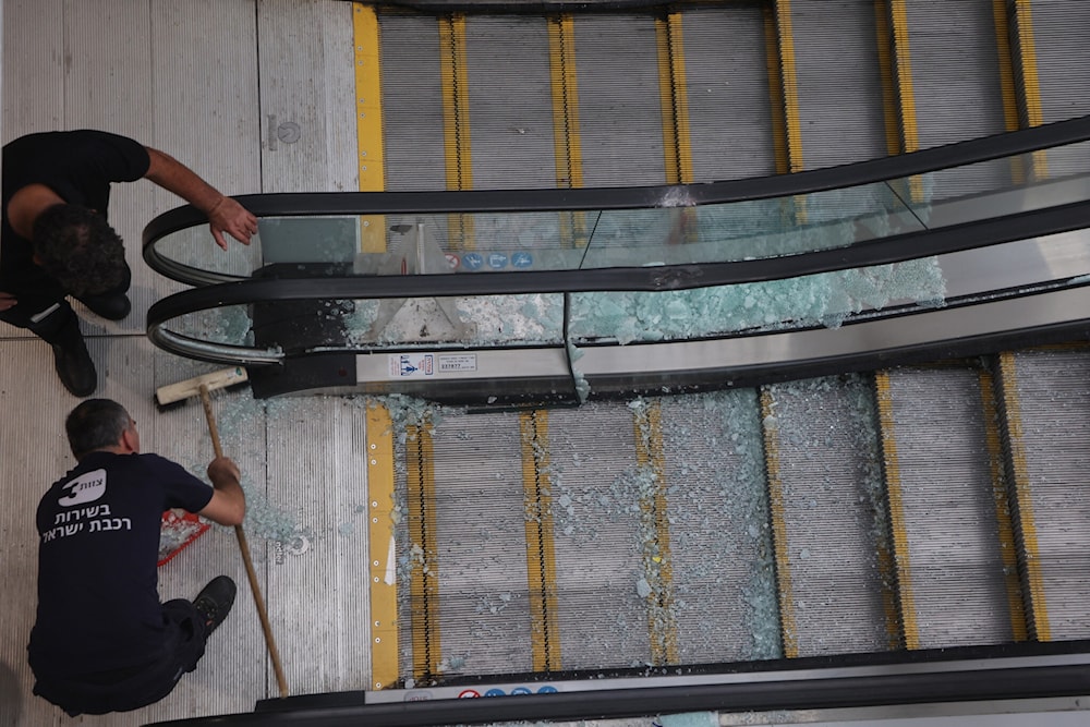 Employees sweep shards of glass from an escalator damaged from the impact of a missile fired from Yemen, inside a train station near Modiin on September 15, 2024. (AFP)