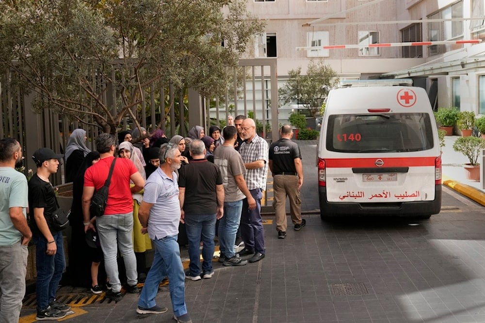 Lebanese Red Cross ambulance passes next to the families of victims who were injured on Tuesday by their exploding handheld pagers, at the emergency entrance of the American University Hospital, in Beirut, Lebanon, Wednesday, Sept. 18, 2024. (AP)