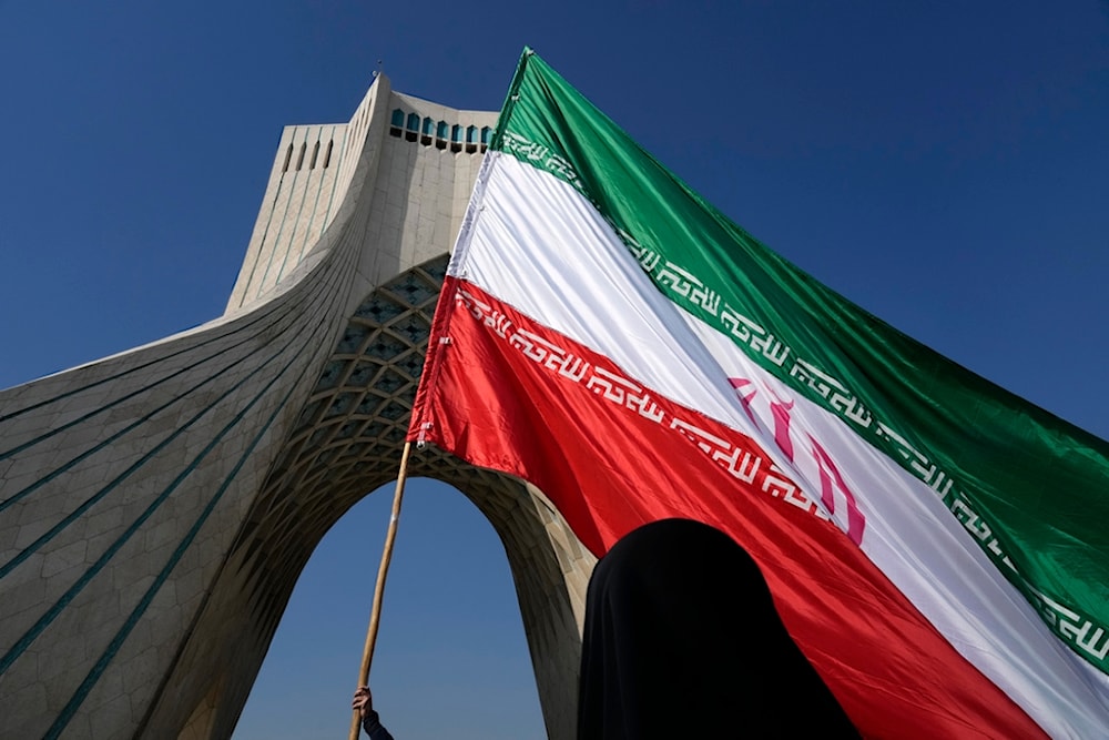 A huge Iranian flag is carried under the Azadi (Freedom) monument tower during the annual rally commemorating Iran's 1979 Islamic Revolution in Tehran, Iran, Sunday, Feb. 11, 2024. (AP)