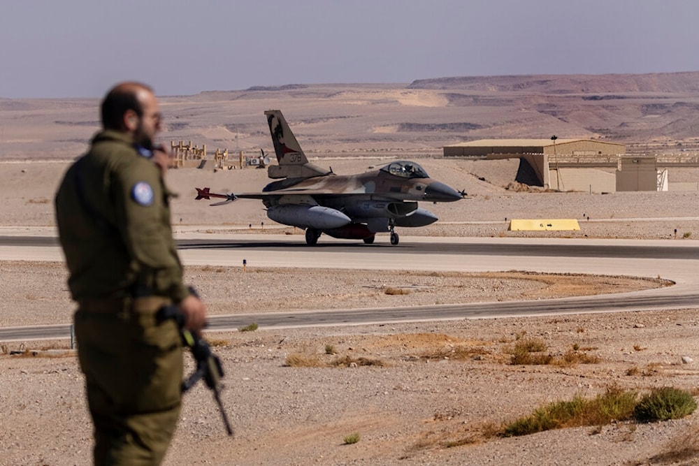 An Israeli officer watches as an Italian Air Force F-16 taxis at Ovda airbase near Eilat, southern occupied Palestine, Sunday, October 24, 2021 (AP) 