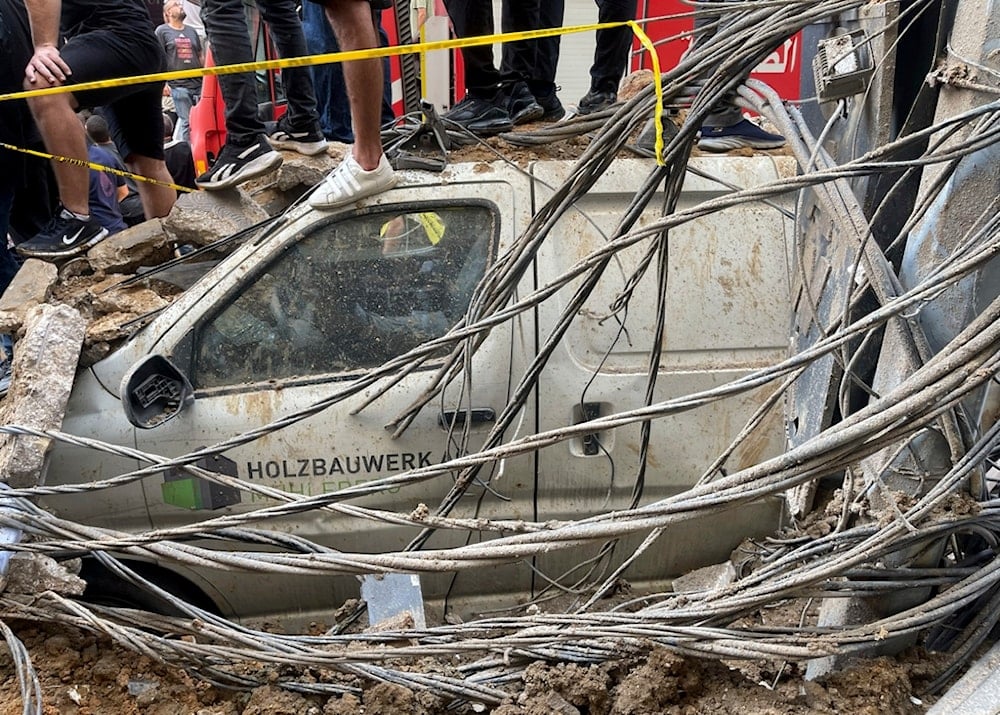 People stand on top of a damaged car at the scene of a missile strike in the southern suburbs of Beirut, Friday, Sept. 20, 2024. (AP Photo/Bilal Hussein)