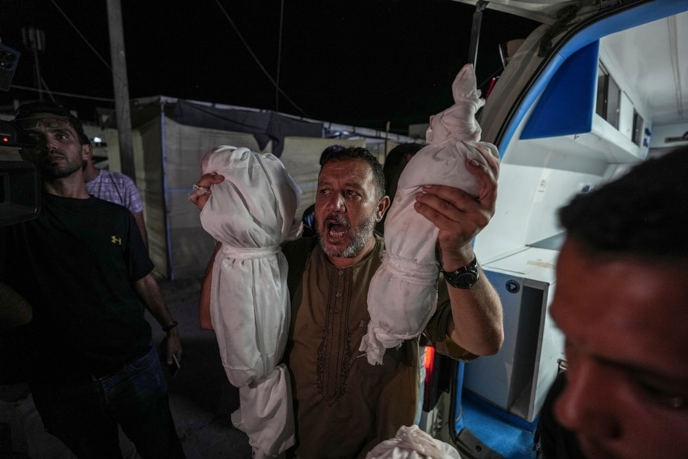 Osama al-Taweel holds up the bodies of his grandchildren who were killed in an Israel airstrike on the Gaza Strip, as he arrives at the hospital morgue in Deir al-Balah, in Palestine, on August 29, 2024. (AP)