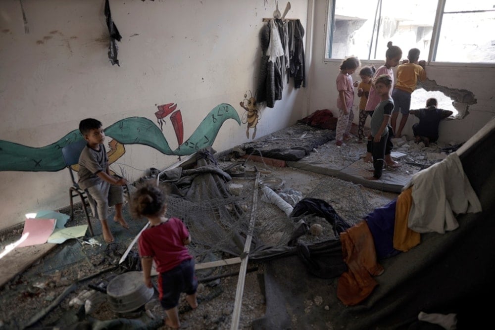 Palestinian children navigate heavy damage to a UNRWA school sheltering forcibly displaced Palestinians in Khan Younis, southern Gaza Strip, on Friday June 21, 2024. (AP)