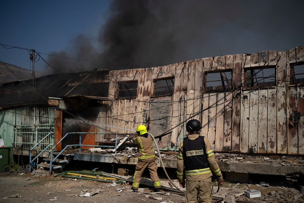 Firefighters work to extinguish a fire after a rocket, fired from Lebanon, hit a local municipality storage in Kiryat Shmona, northern occupied Palestine, September 24, 2024 (AP)