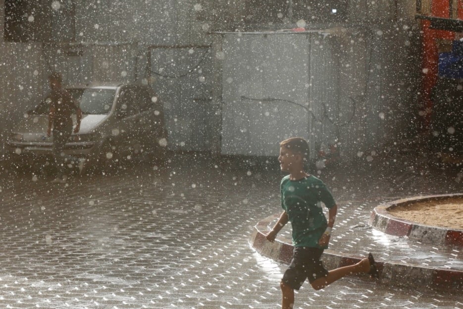 A forcibly displaced Palestinian child running under the rain on September 3,2024. (UNRWA)