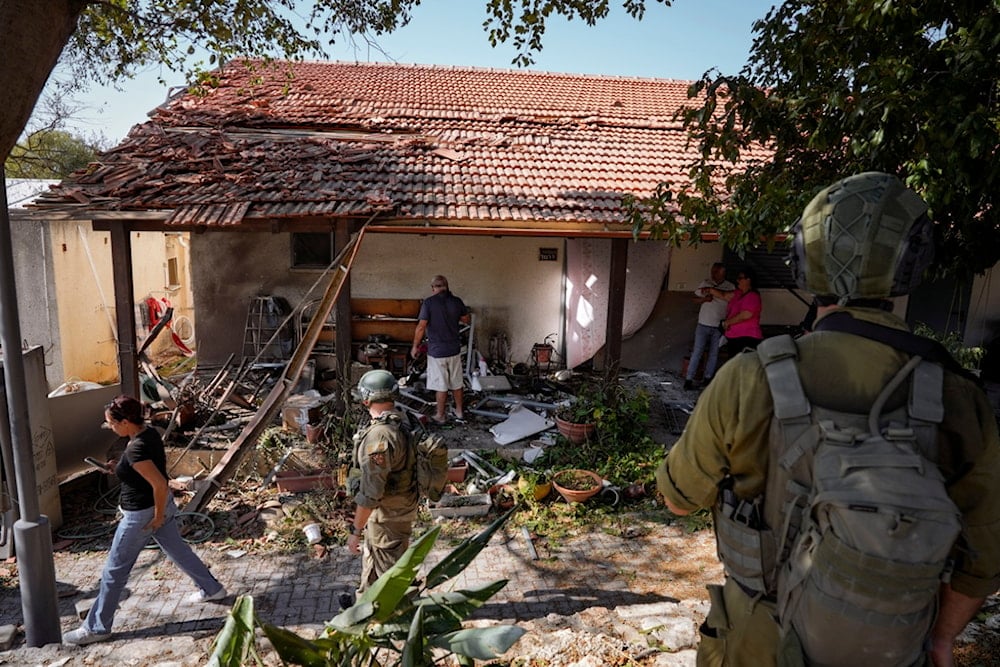 Israeli occupation forces, settlers examine a house that was hit by a rocket fired from Lebanon, in Kibbutz Saar, northern occupied Palestine, on Wednesday, September 25, 2024 (AP)