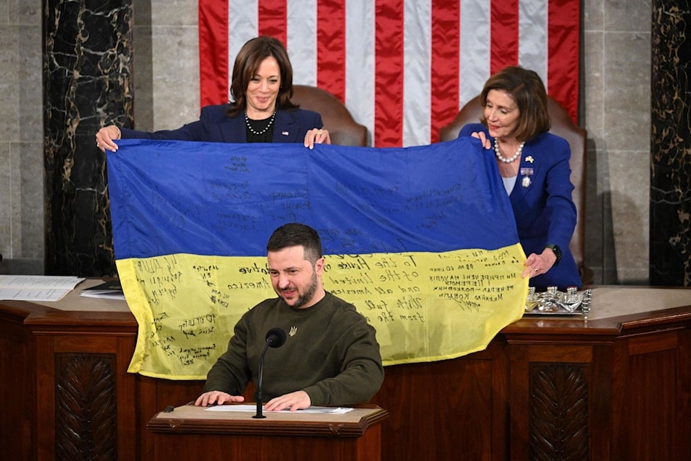 President Volodymyr Zelensky addresses Congress as Rep. Nancy Pelosi and Vice President Kamala Harris hold up a Ukrainian national flag signed by Ukrainian soldiers at the Capitol in Washington on Wednesday, December 21. (AFP/Getty Images)