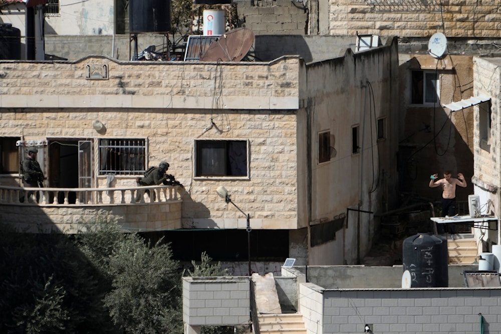 A man holds his hand while in the sight of two Israeli soldiers in the West Bank town of Qabatiya during a raid, Thursday, September 19, 2024 (AP)