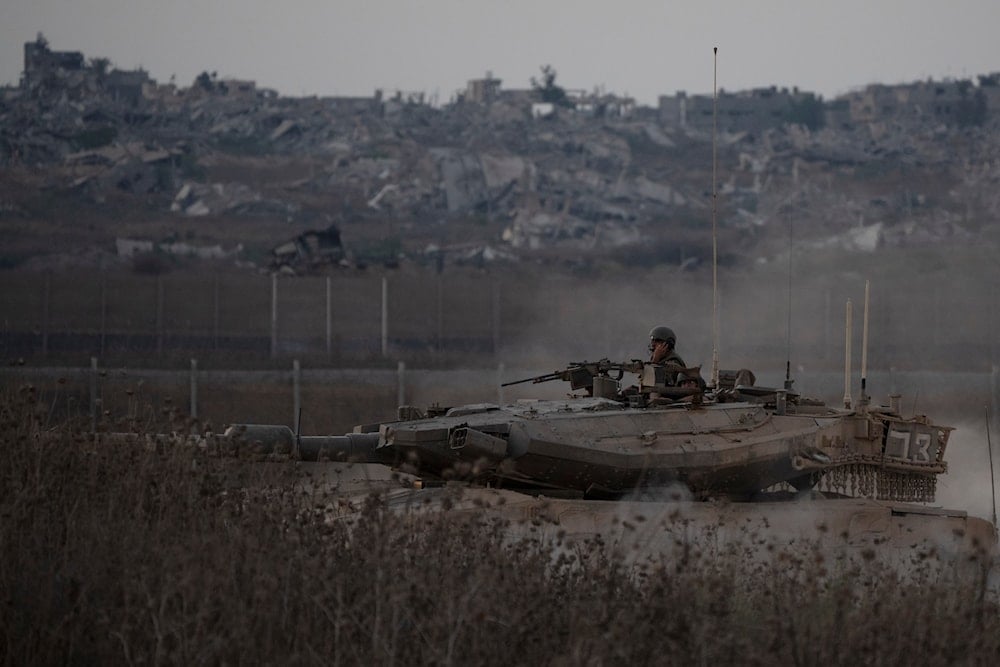 Israeli soldiers move on the top of a tank near the Gaza border, as seen from southern occupied Palestine, on August 21, 2024. (AP)