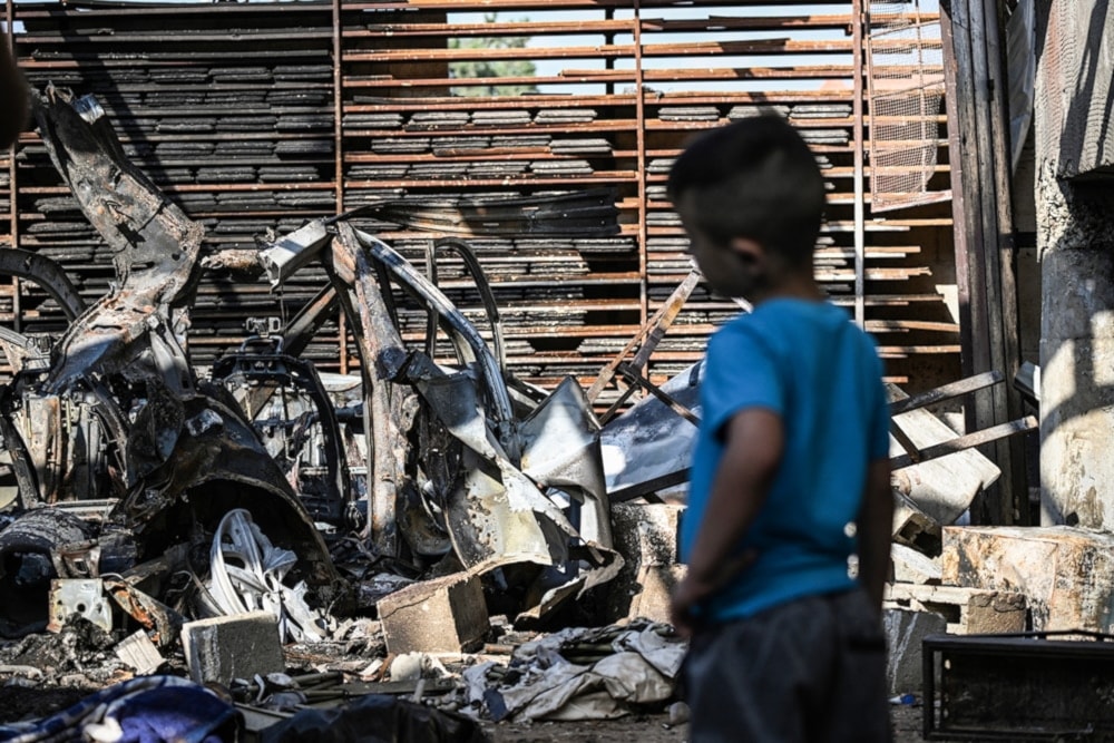 A Palestinian child stares at a car, destroyed by Israeli occupation forces, inside the garage of a home in Jenin in the occupied West Bank, occupied Palestine, on August 31, 2024. (AFP)