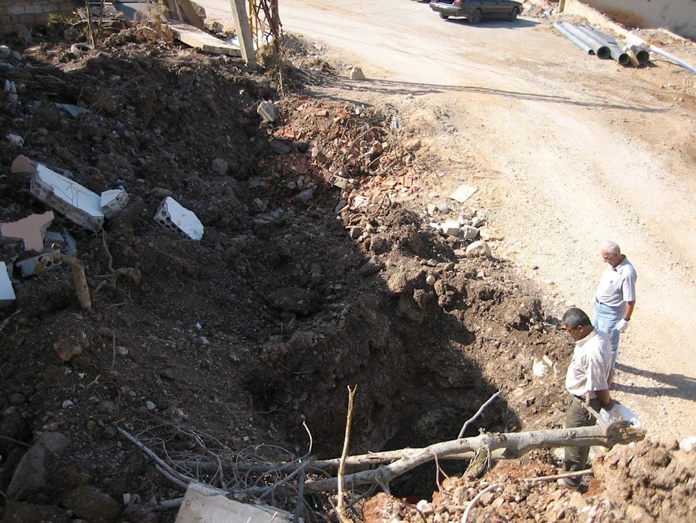 Dr Ali Khobeisi (right) taking Geiger counter readings at a bomb crater in Khiam, Lebanon 2006.