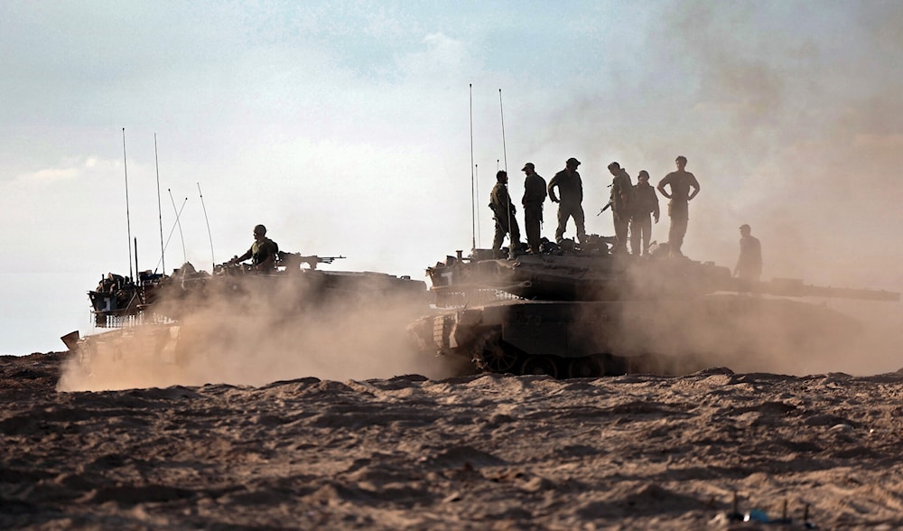 IOF soldiers and tanks gather in a field near Kibbutz Be'eri on October 14, 2023. (AFP)