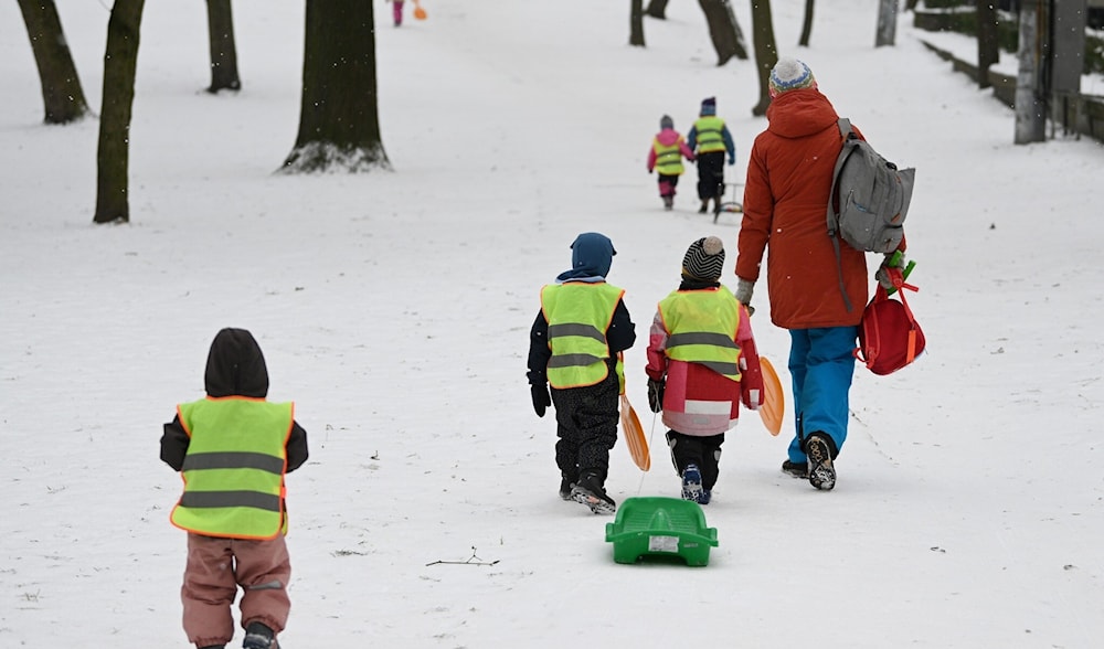 Young children pull a sled as they walk up a slope through snow in the western Ukrainian city of Lviv on February 7, 2023. (AFP)