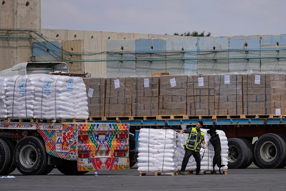 Trucks carrying humanitarian aid for the Gaza Strip pass through the inspection area at the Karem Salem Crossing in southern occupied Palestine, Thursday, March 14, 2024. (AP)