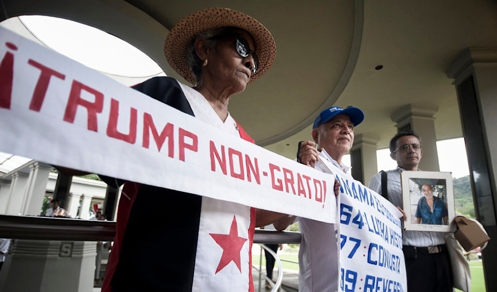 A woman holds up a banner with a message that reads in Spanish; 