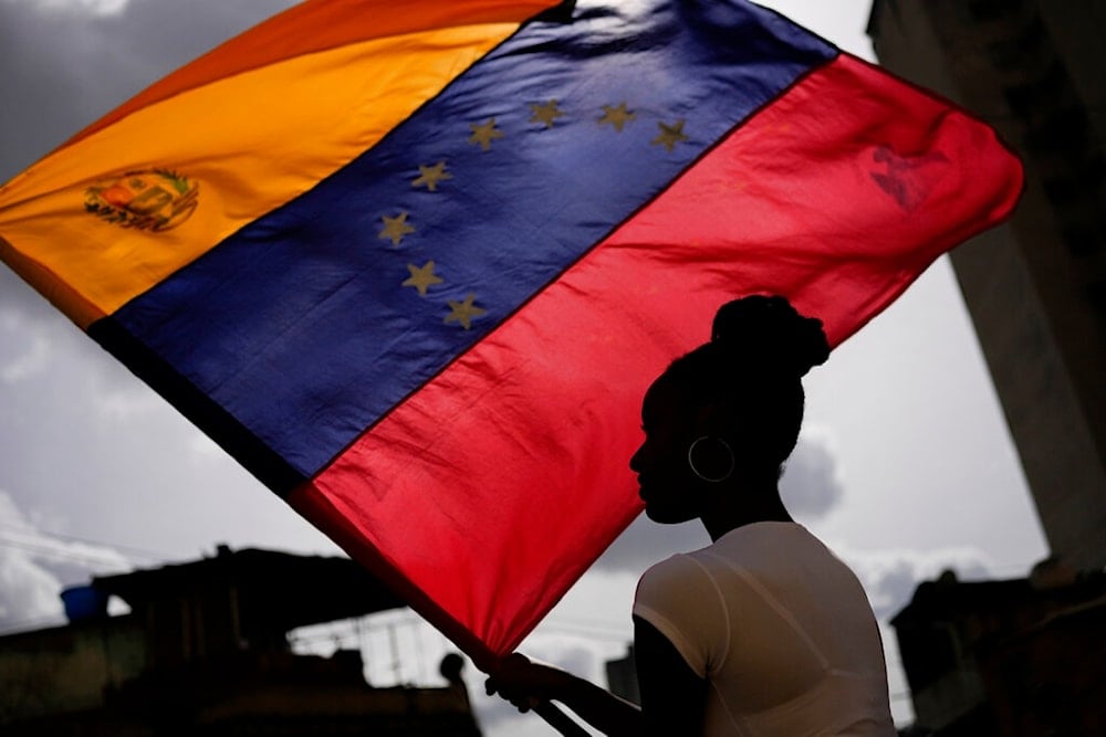 A woman holds a Venezuelan flag during the Saint John the Baptist feast in the San Agustin neighborhood of Caracas, Venezuela, Friday, June 24, 2022. (AP Photo/Matias Delacroix)