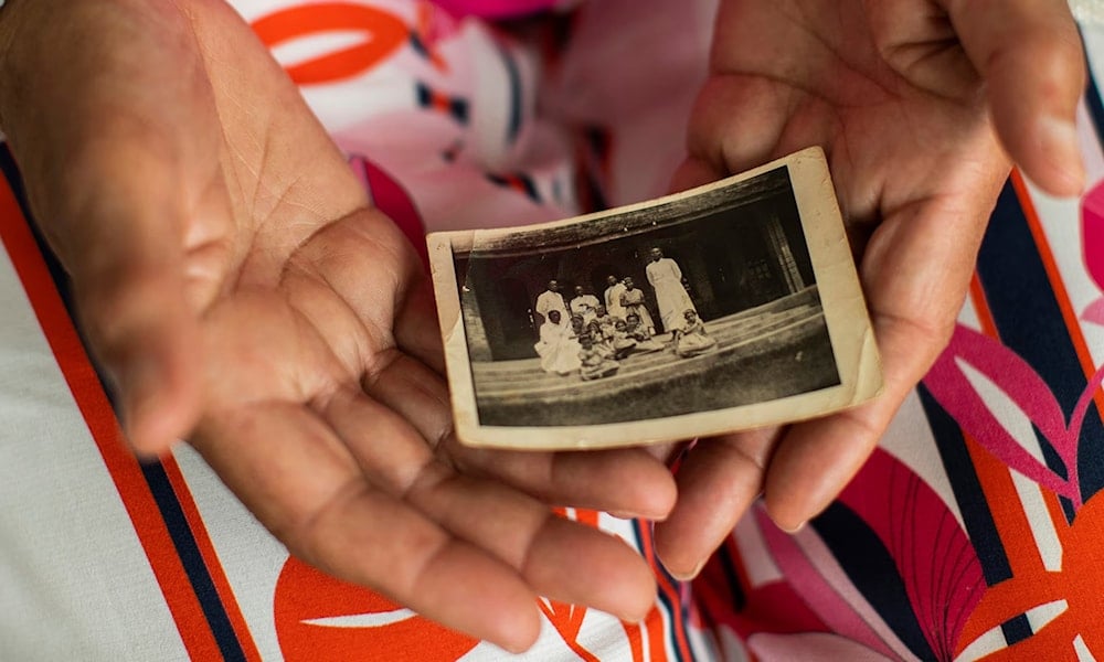 Monique Bitu Bingi, one of the plaintiffs in the case, holds holds a photo of herself as a young girl before she was forcibly removed from her parents. Photograph: Francisco Seco/AP