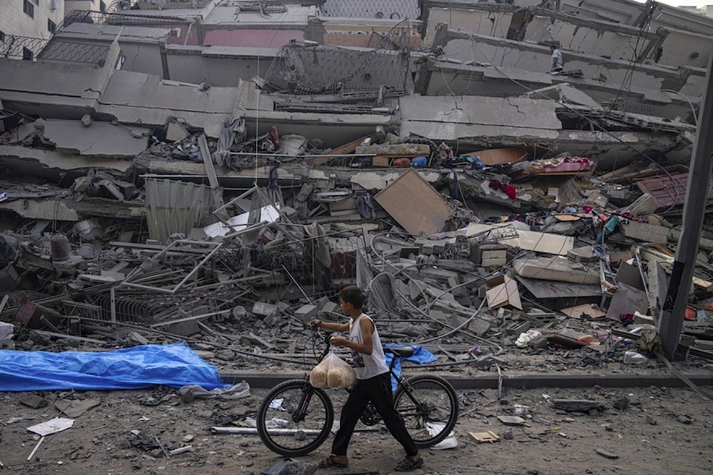 A Palestinian child walks with a bicycle by the rubble of a building after it was hit by an Israeli airstrike in Gaza City October 2023, (AP)