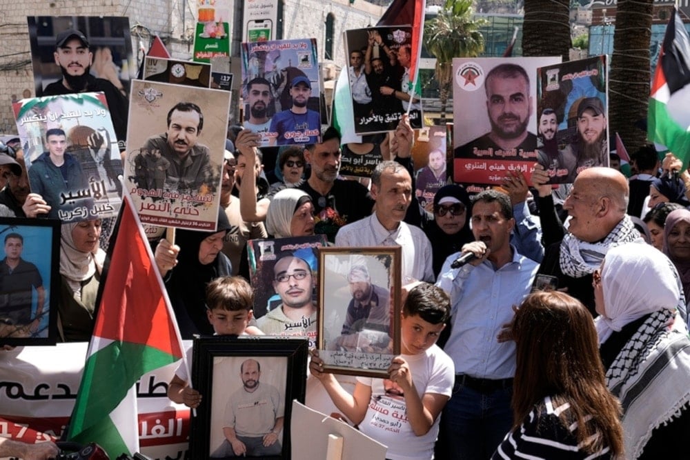 Palestinians hold photographs of detainees held by the Israeli occupation during a rally marking the annual prisoners’ day in the West Bank city of Nablus, on April 17, 2024. (AP)