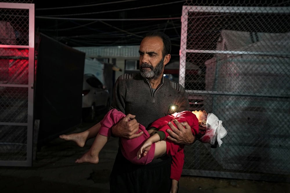 A Palestinian man carries a wounded girl, following an Israeli bombardment on the Gaza Strip, as they arrive at the Al-Aqsa Martyrs hospital in Deir al-Balah, on Janaury 14, 2025. (AP)