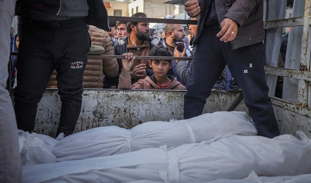 A boy looks at the bodies of Palestinians killed in the Israeli bombardment of the Gaza Strip as they are brought for burial at Al-Aqsa Hospital in Deir al-Balah, Wednesday, Jan. 15, 2025. (AP)