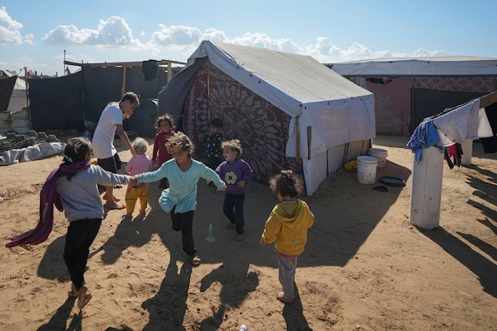 Children play next to their tent in a refugee camp in Deir al-Balah, Gaza Strip, on November 19, 2024 (AP)