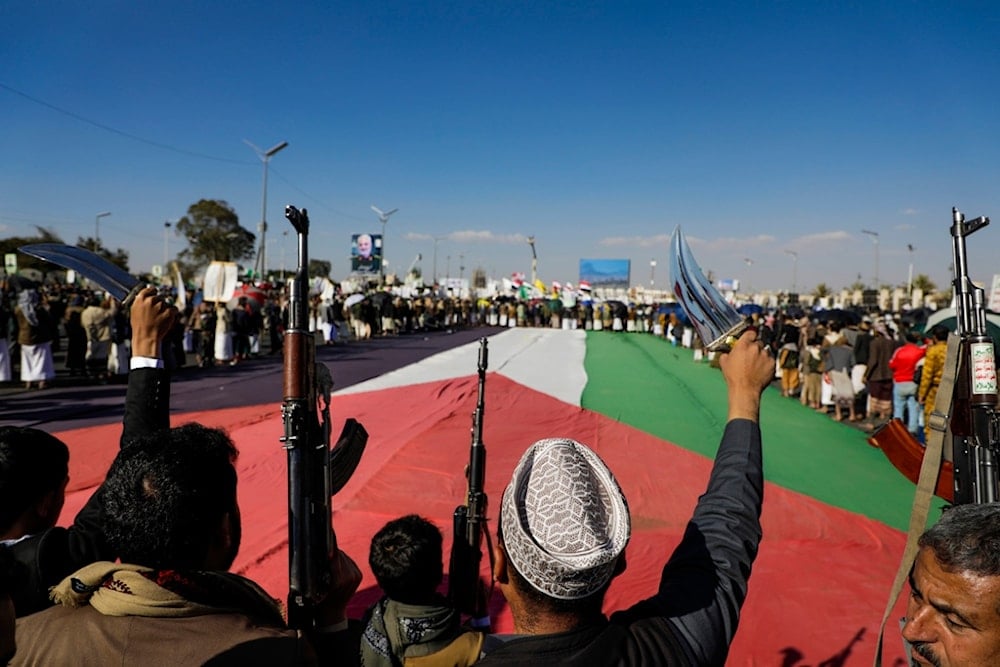 People gather around a giant Palestinian flag during an anti-Israeli rally in Sanaa, Yemen, Friday, Jan. 10, 2025 (AP)