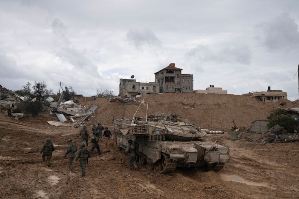 IOF soldiers walk by a tank during the ground invasion of the Gaza Strip in Khan Younis on Saturday Jauary 27,2024. (AP)