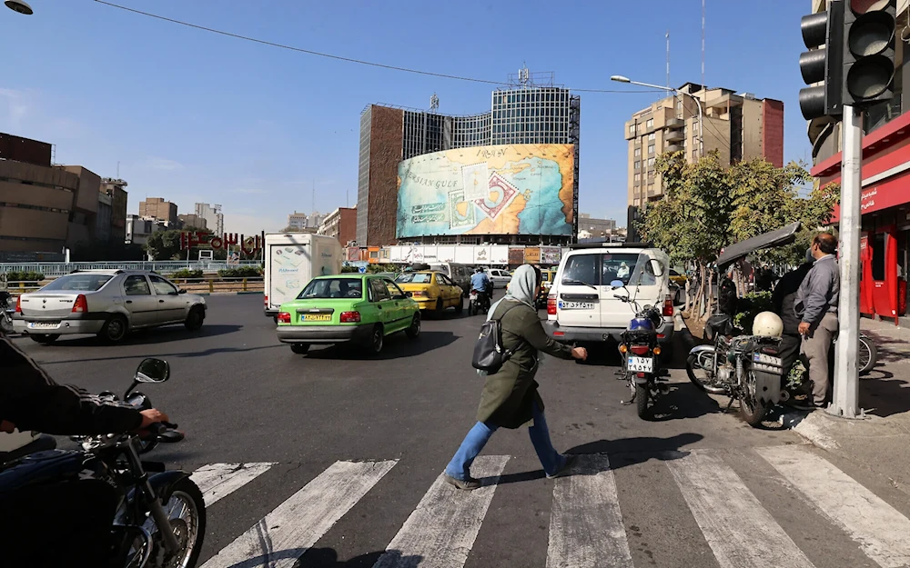 People walk and drive past a billboard covering the facade of a building on Vali-Asr square in Tehran, Iran, October 26, 2024. (AFP)