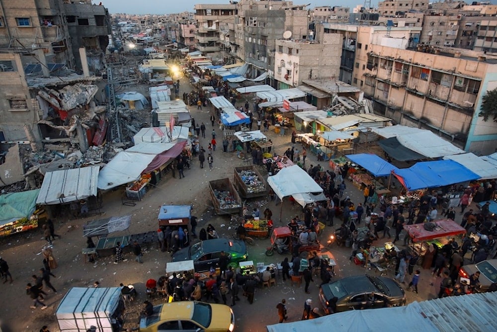 Palestinians walk along a street market in Khan Younis, central Gaza Strip, Saturday, Jan. 18, 2025 (AP)