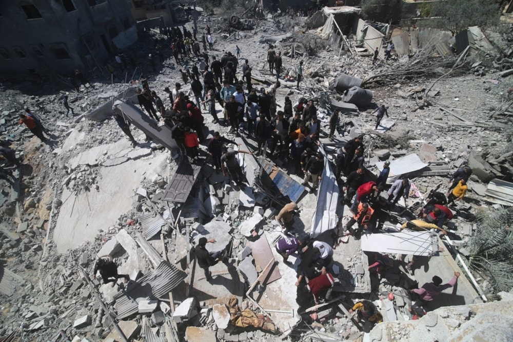 Palestinians look at residential building, destroyed by an Israeli strike in Rafah on March 20, 2024. (AP)