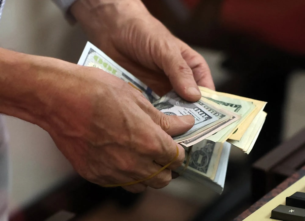 A man holds a mix of dollar and euro banknotes (AFP via Getty Images)