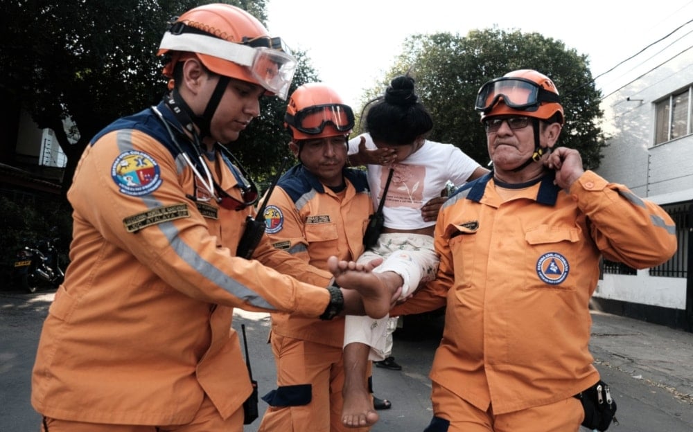 Civil defense members help a child as displaced people from recent clashes between armed groups take shelter at the General Santander Stadium in Cucuta, Norte de Santander Department, Colombia, January 19, 2025. (AFP)